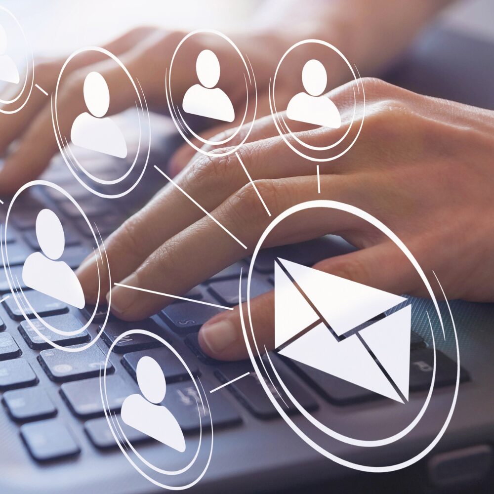 A person typing with an email icon connected to various user icons.