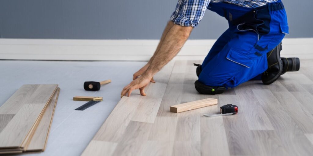 A contractor laying down wooden tiles.