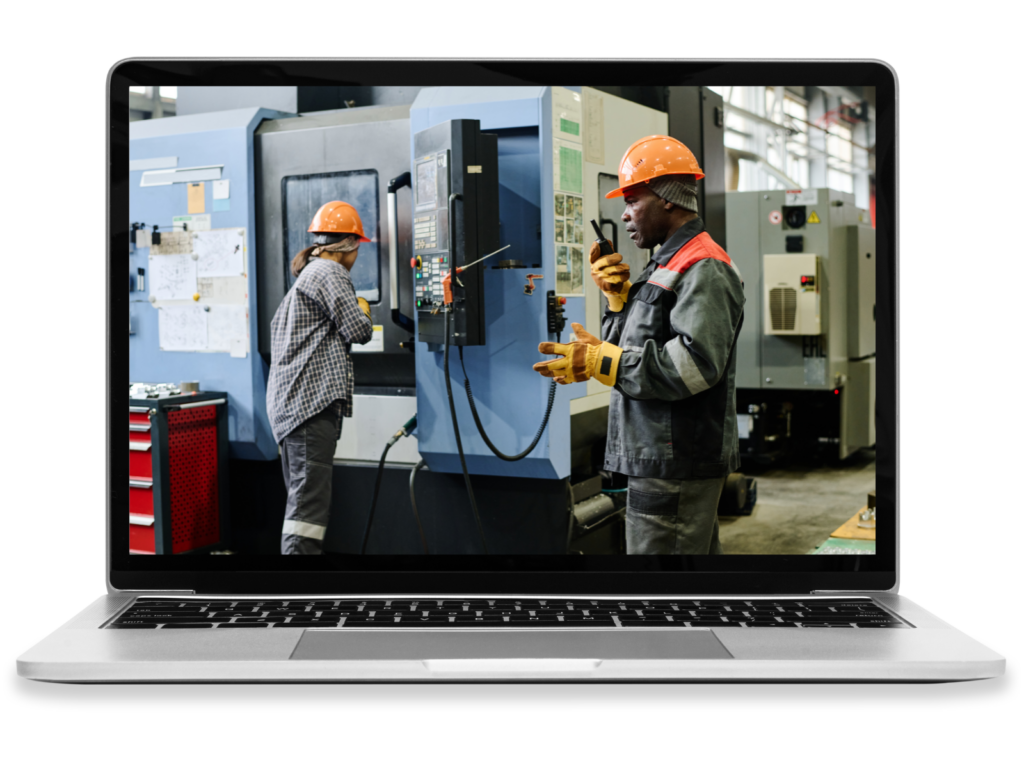 A laptop displaying workers operating machinery in an industrial shop